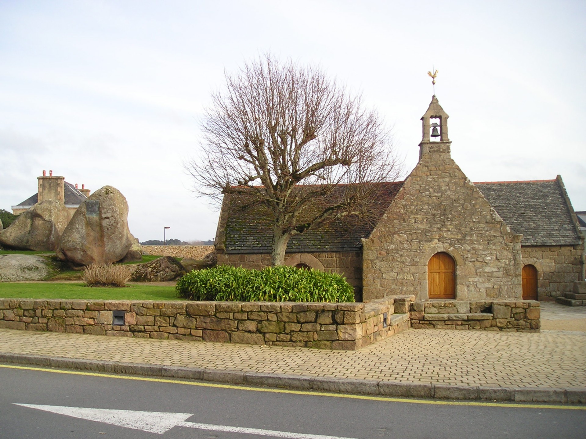 Photo avant : la chapelle Sainte-Anne intacte, sa toiture d'ardoise et son clocheton, parmi les rochers de granit rose.